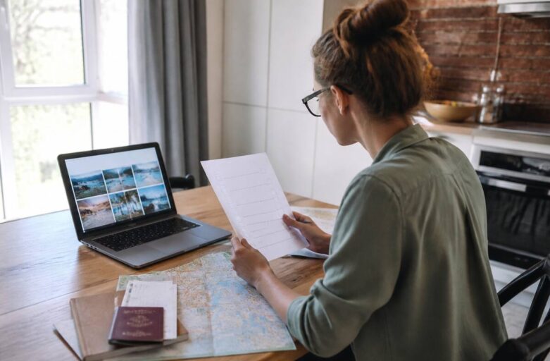 Vakantie checklist invullen terwijl iemand vakantieopties vergelijkt op laptop